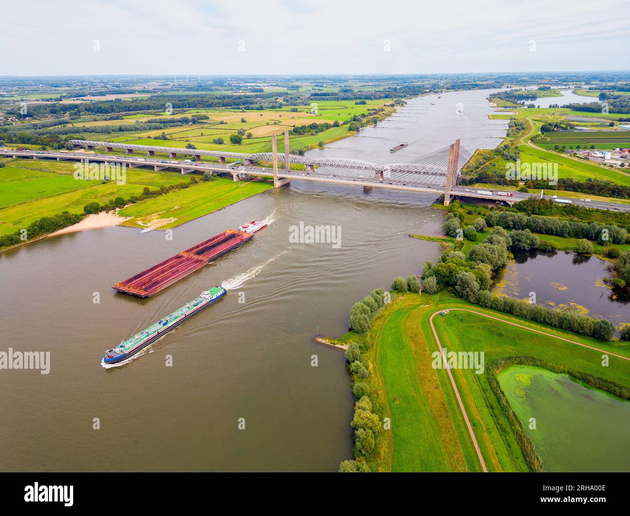 Hochwinkel-Drohnen-Point of View auf Frachtschiffen, die am Sommertag auf dem Waal River in Zaltbommel, Gelderland, Niederlande segeln Stockfoto