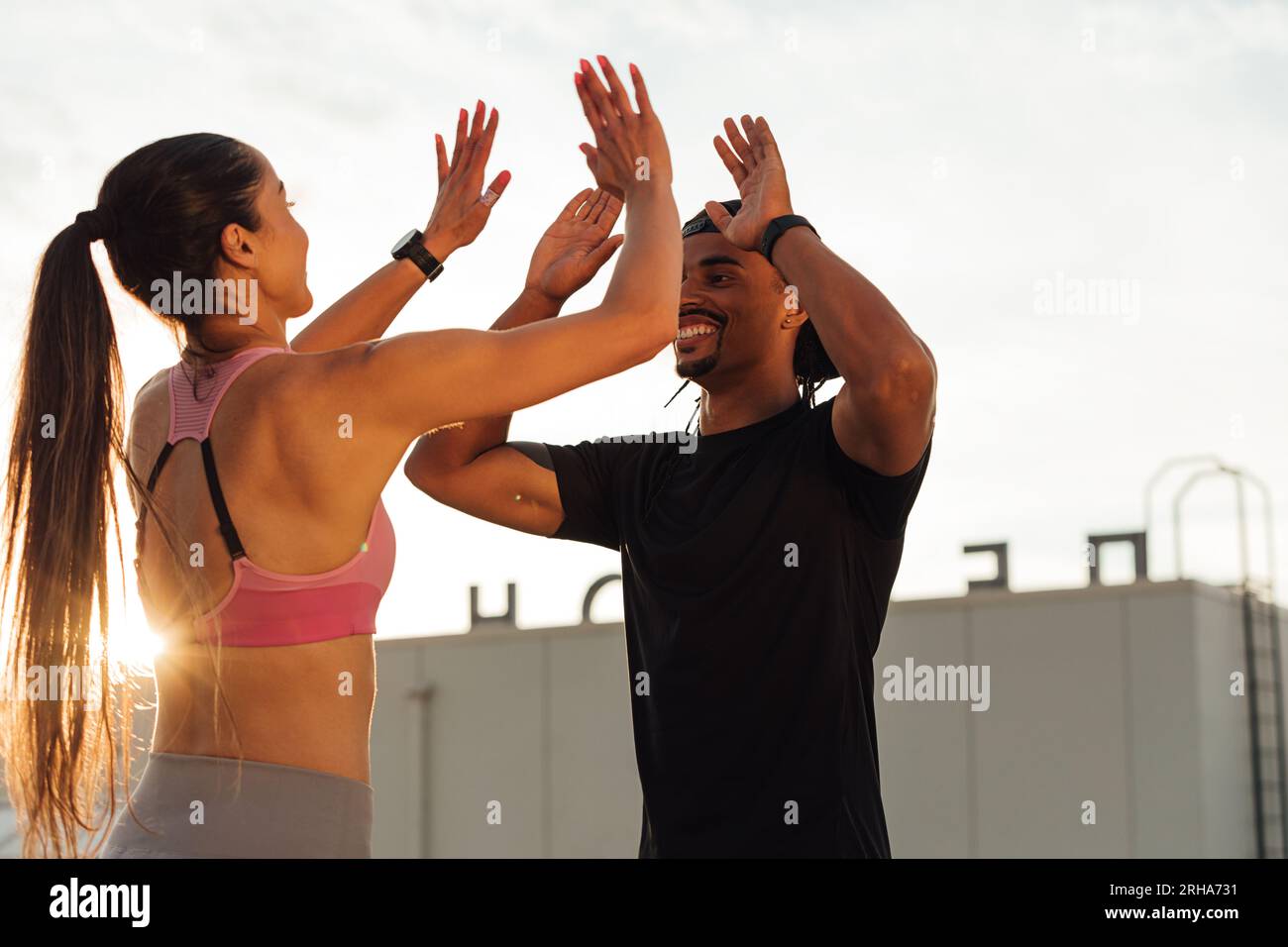 Ein Mann und eine Frau, die während eines Trainings auf dem Dach High Five machen Stockfoto