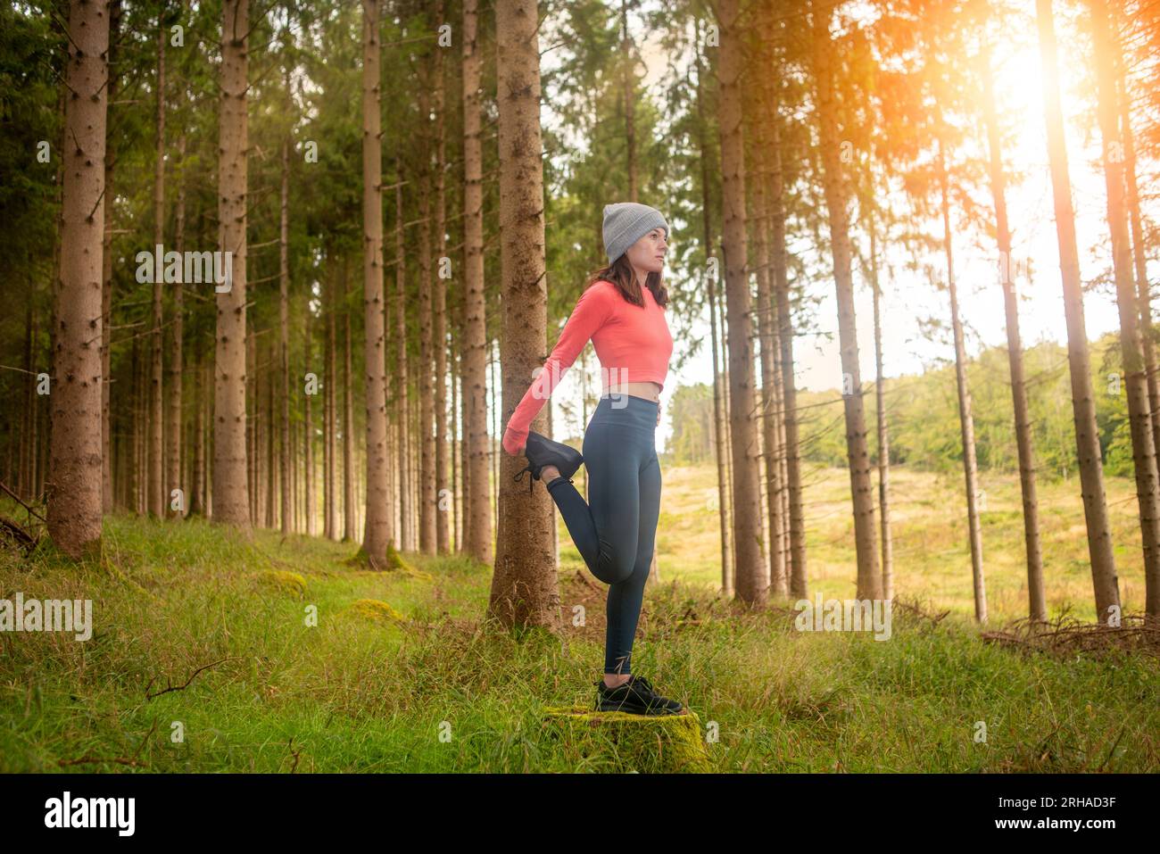 Sportliche Frau, die Beindehnungsübungen macht, draußen im Wald. Outdoor-Trainingskonzept. Stockfoto