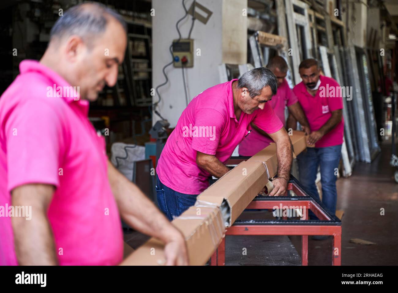 Arbeiter, die Kartonkartons für den Versand im Lager verpacken. Ein Bediener schließt einen Karton mit Klebeband in einem Lager. Stockfoto