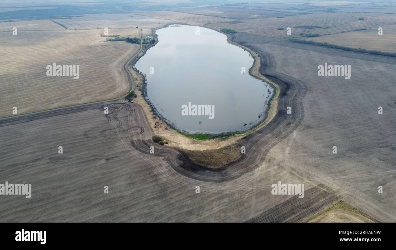 Remote Saskatchewan: Luftdrohnenaufnahme von ruhigem Wasser in arider brauner Landschaft. Der Kontrast der Natur in einer abgeschiedenen ländlichen Umgebung Stockfoto