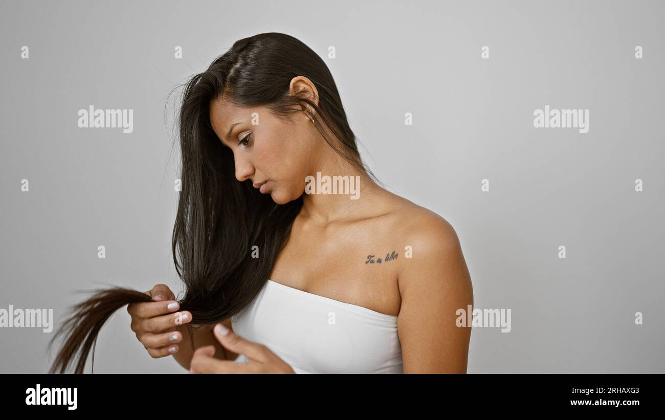 Junge latein-Frau, die Haare untersucht, die verärgert über isolierten  weißen Hintergrund aussehen Stockfotografie - Alamy