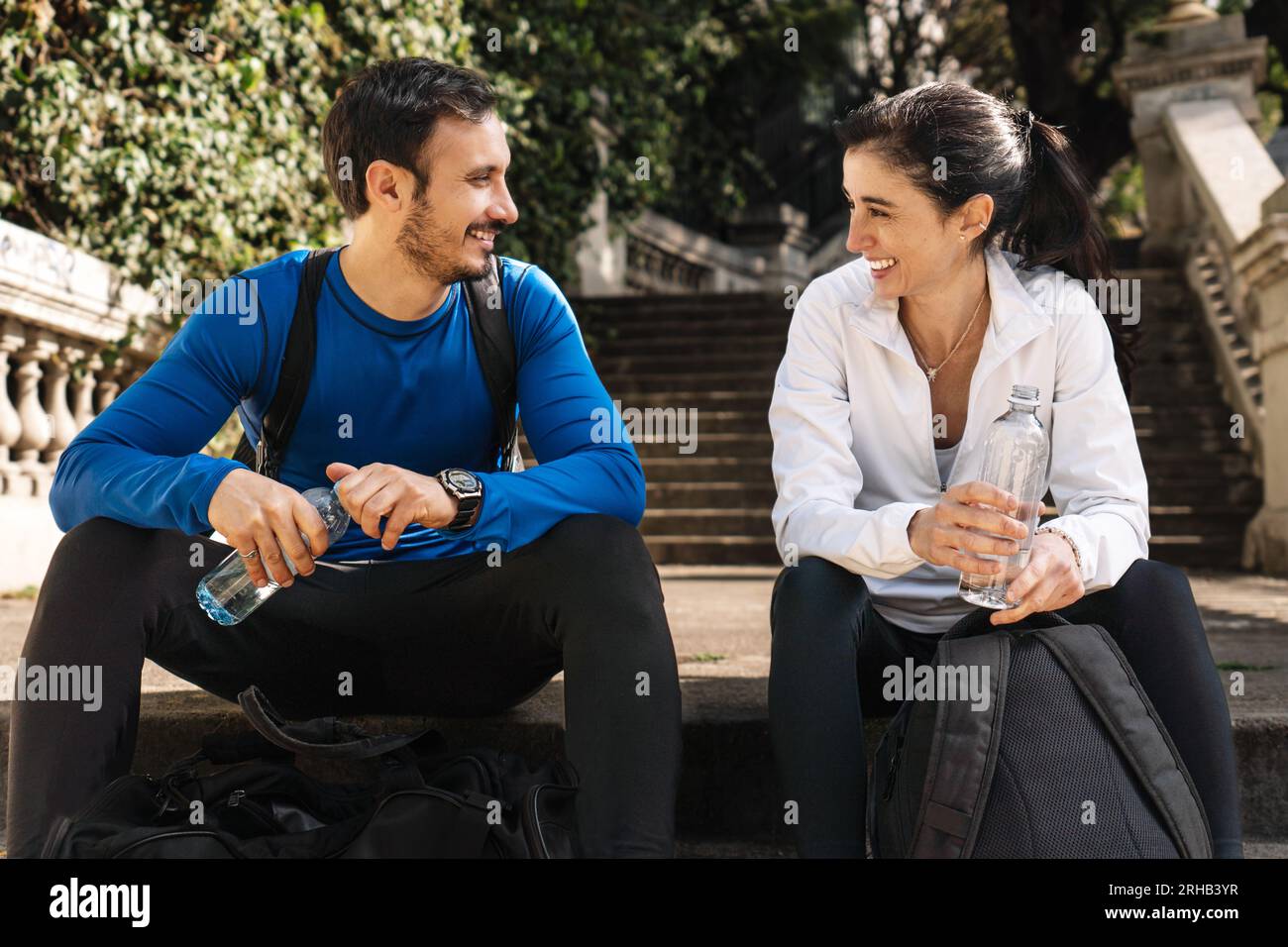 Mann und Frau ruhen sich nach dem Joggen auf den Stufen eines Parks aus. Stockfoto