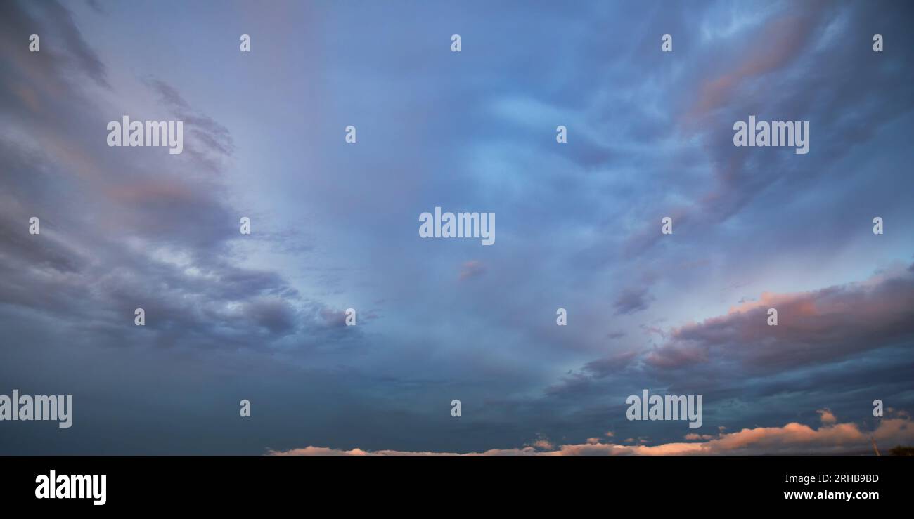 Die donnernde Geschichte der Dämmerung: Ein stürmischer Himmel Aglow mit untergehender Sonne Stockfoto