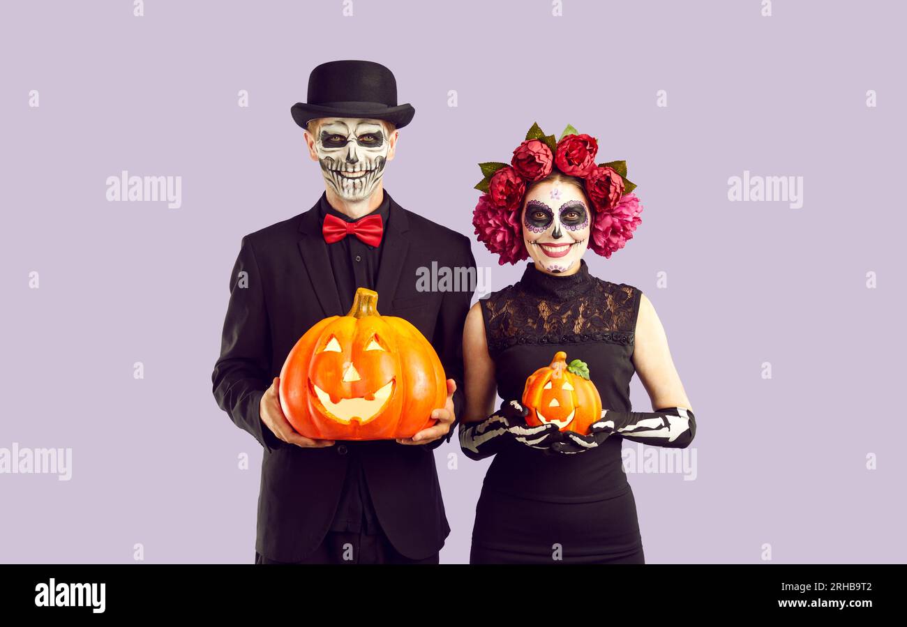 Glückliches Paar in Skelettkostümen mit Halloween-Kürbissen und lächelndem Lächeln Stockfoto