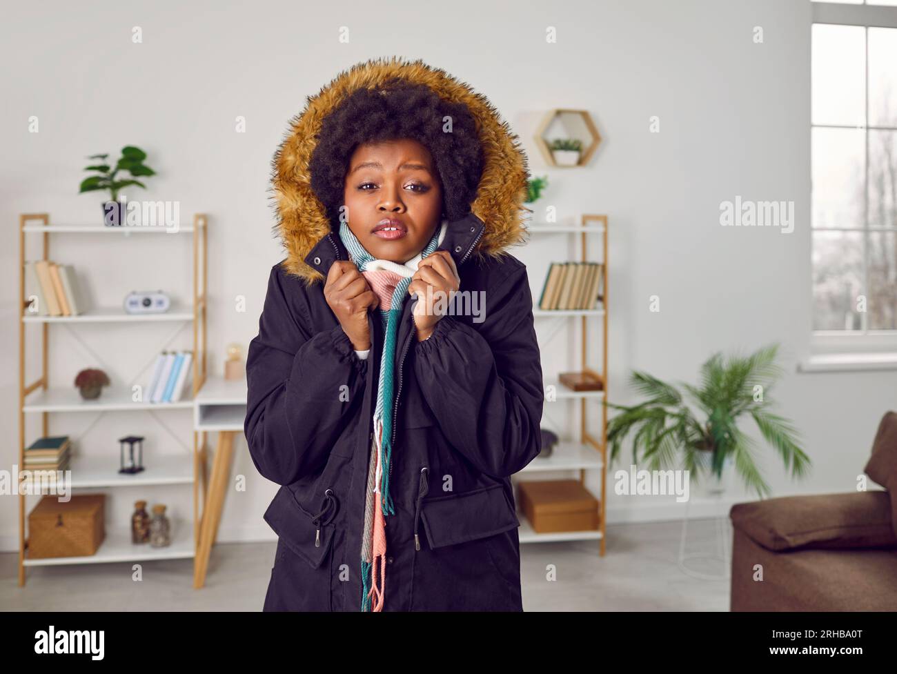 Afroamerikanisches Mädchen in Winterjacke, das in einer kalten Wohnung friert Stockfoto