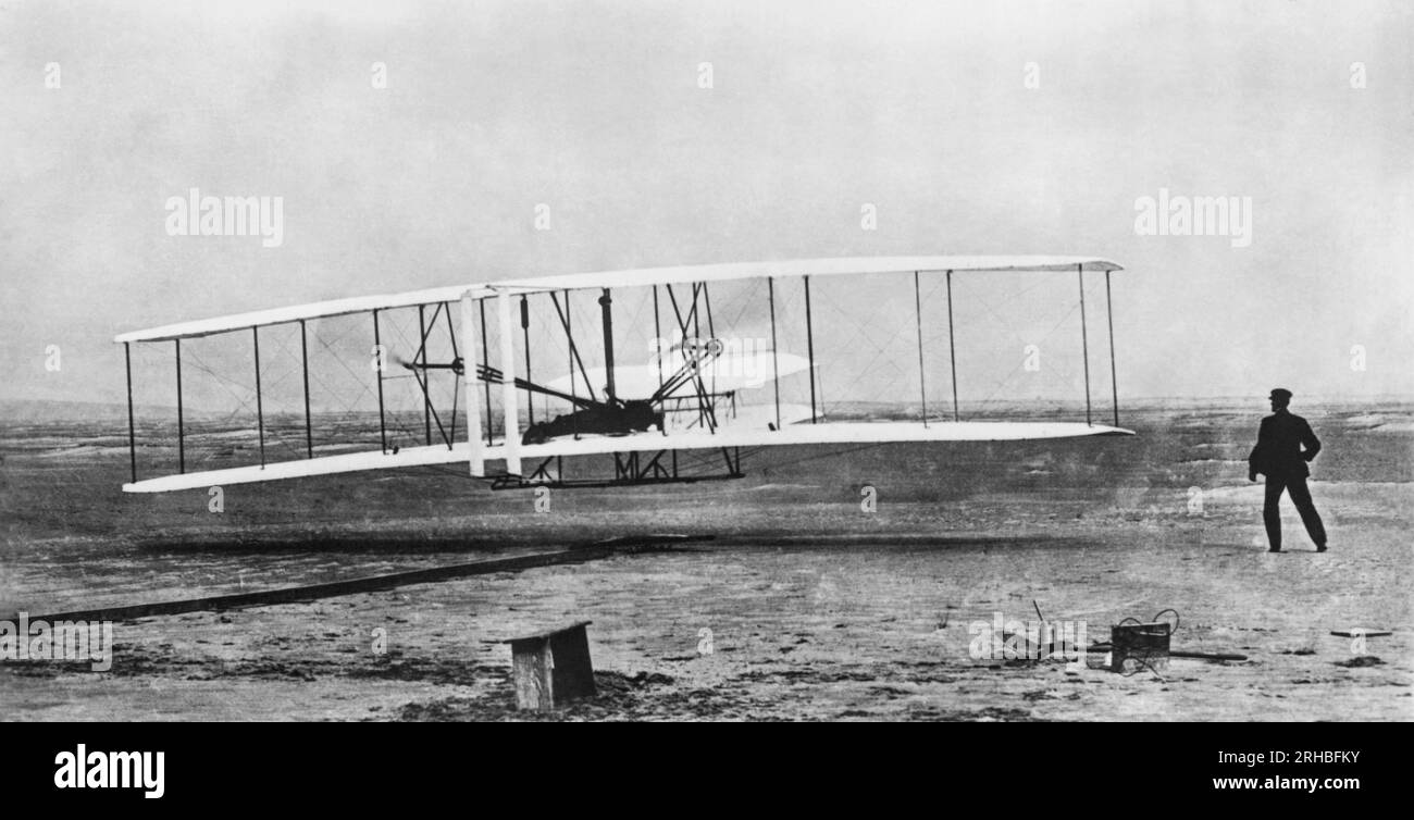 Kitty Hawk, North Carolina: 17. Dezember 1903 Orville Wright fliegt während des ersten angetriebenen und anhaltenden Fluges, während Wilbur auf der rechten Seite am Boden liegt. Stockfoto