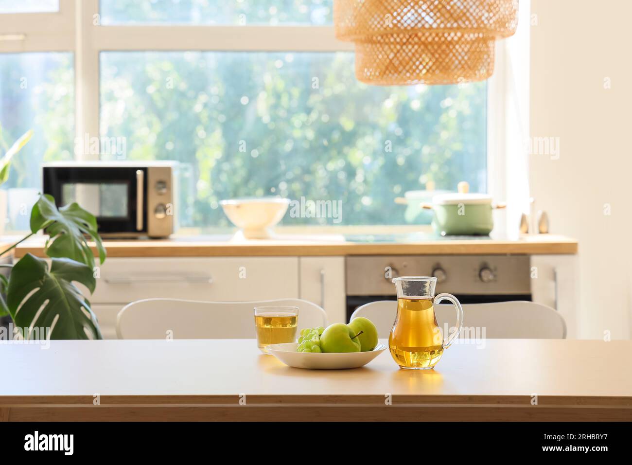Kanne mit einem Glas Saft und Obst auf dem Esstisch in der Küche Stockfoto