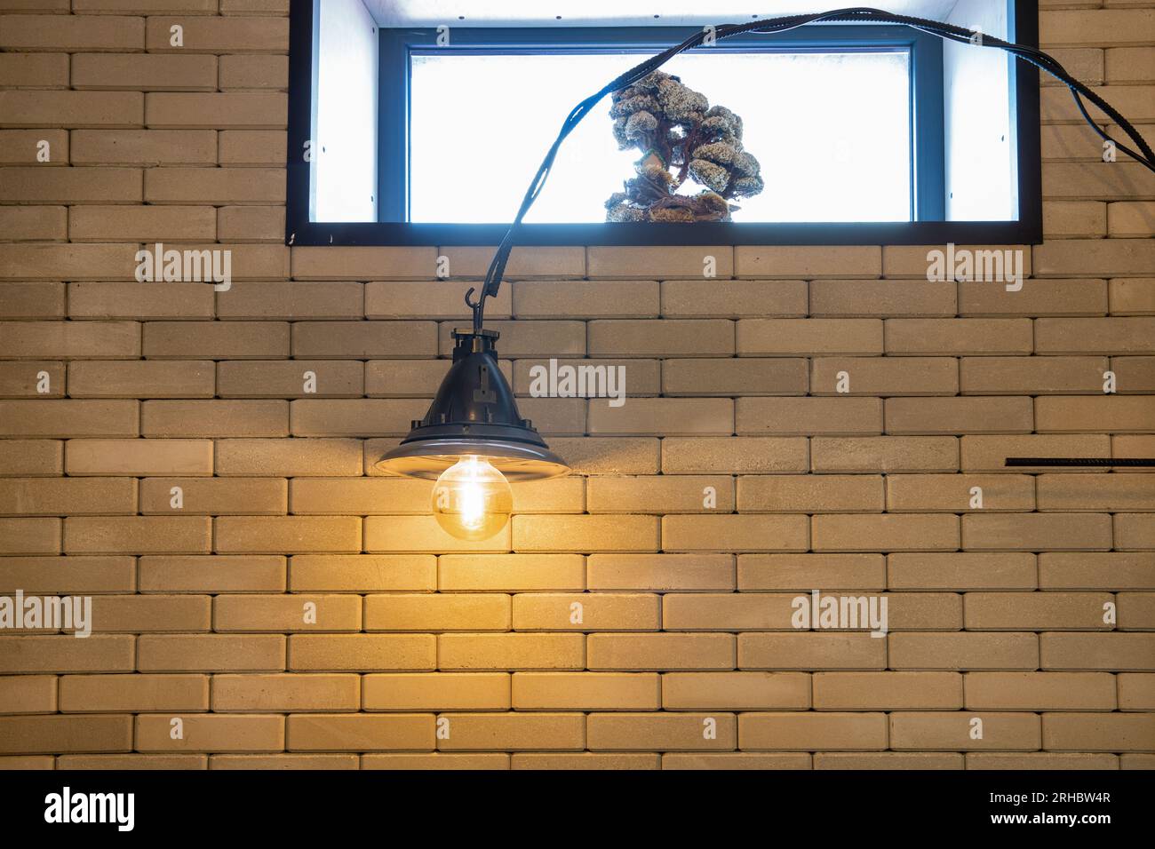 Elektrische Loftlampe im minimalistischen Stil gegen Fenster und Ziegelwände im Innenbereich Stockfoto