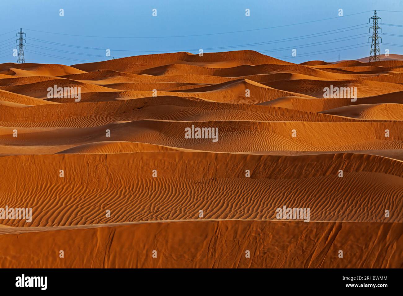 Strommasten inmitten orangefarbener Sanddünen in der Wüste, Saudi-Arabien Stockfoto