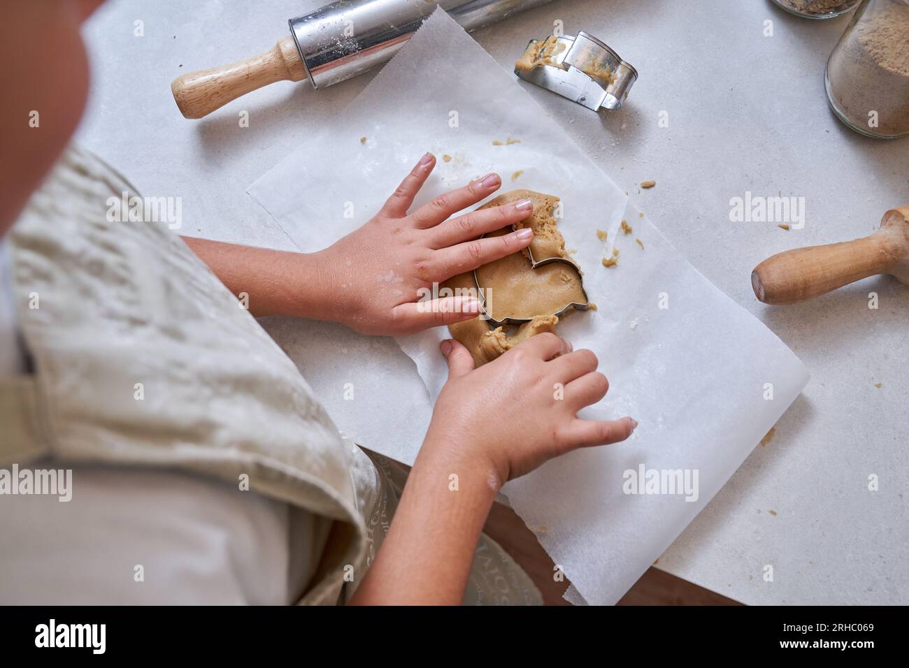 Teig mit hohem Erntewinkel für die anonyme Verarbeitung von Kindern mit Schneidewerkzeug, während Sie handgemachte Kekse auf dem Tisch zubereiten Stockfoto