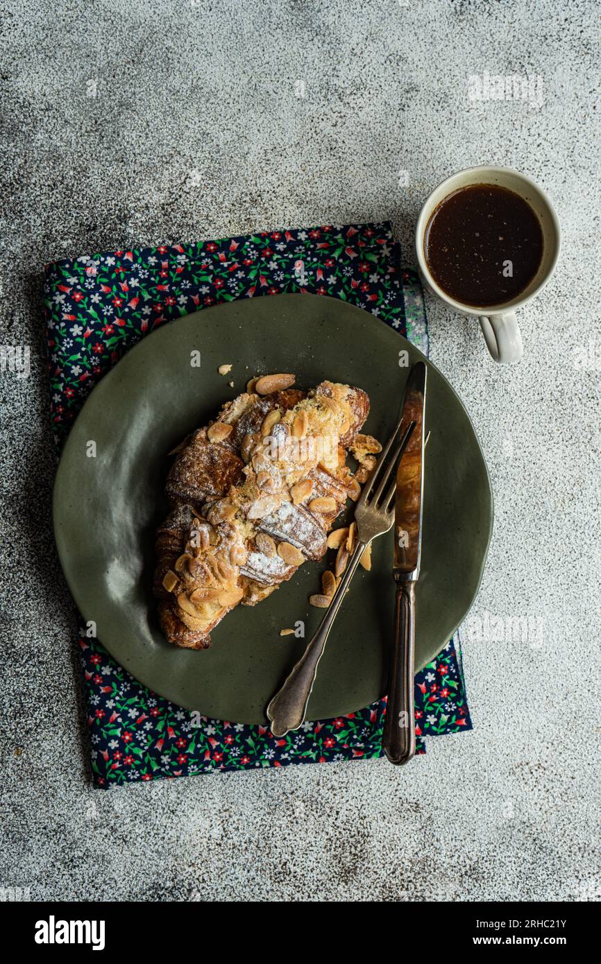Blick von oben auf ein Mandelcroissant mit einer Tasse schwarzem Kaffee Stockfoto