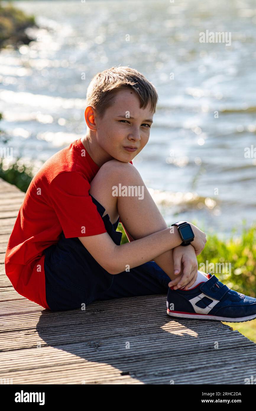 Porträt eines Jungen, der im Sommer am See sitzt Stockfoto