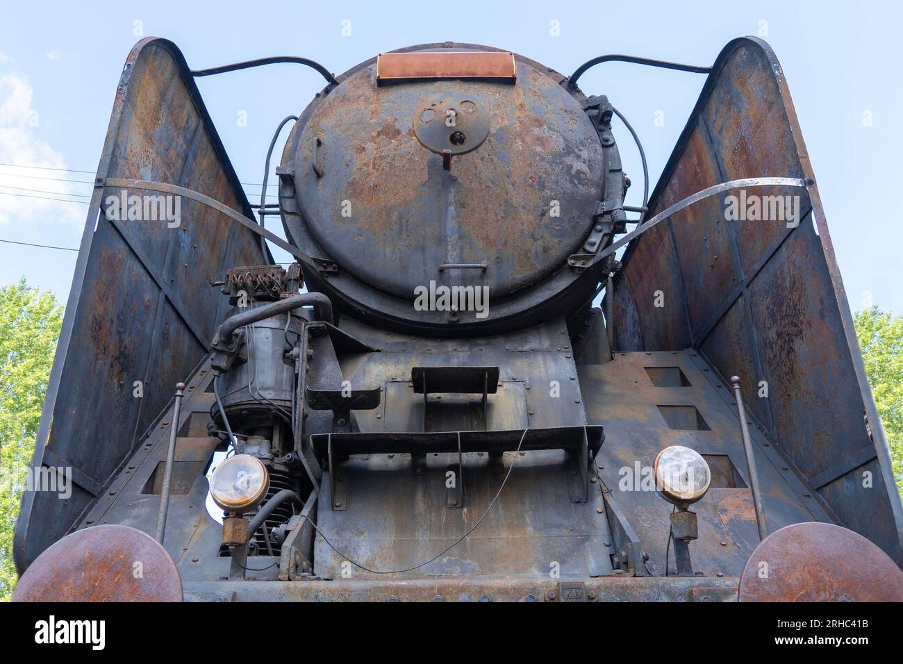 Die Vorderseite einer alten schwarzen, rostigen Dampflokomotive von unten Stockfoto