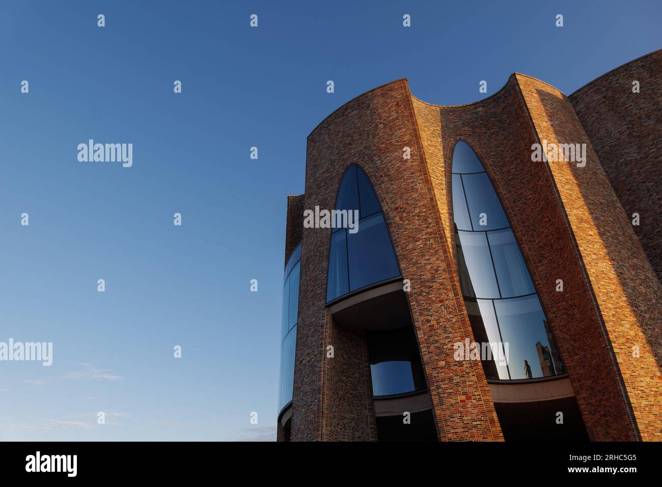 Vejle, Dänemark - 06. OKTOBER 2022: Außenansicht und Details der gebogenen Ziegelwand und Fenster am Fjordenhus während des Sonnenuntergangs. Stockfoto