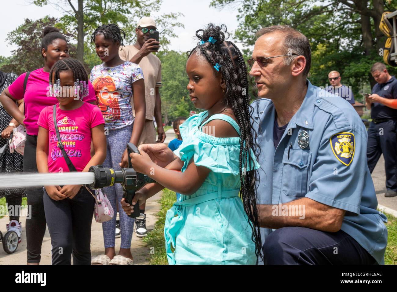 Detroit, Michigan - die Feuerwehr von Detroit erlaubt Kindern, einen Feuerwehrschlauch zu verwenden, während die Bewohner des Stadtviertels Morningside ein Picknick/eine Party veranstalten Stockfoto