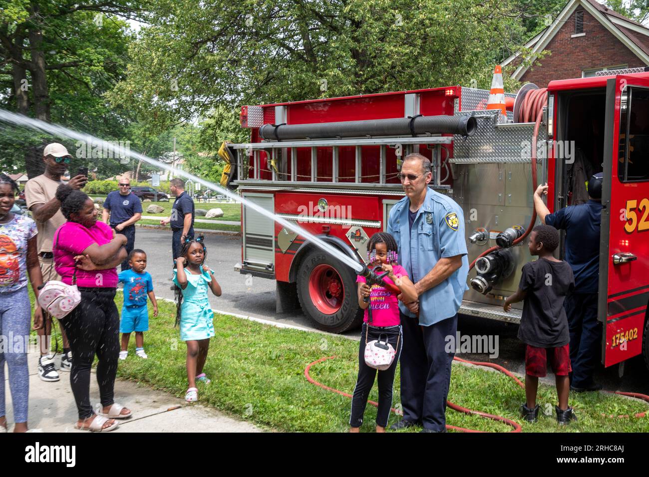 Detroit, Michigan - die Feuerwehr von Detroit erlaubt Kindern, einen Feuerwehrschlauch zu verwenden, während die Bewohner des Stadtviertels Morningside ein Picknick/eine Party veranstalten Stockfoto
