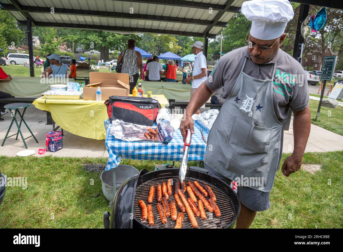 Detroit, Michigan - Adrian Green grillt Hot Dogs, während die Bewohner des Stadtviertels Morningside ein Picknick/eine Party mit dem Namen „Summer Sizzler“ veranstalten. Das war es Stockfoto