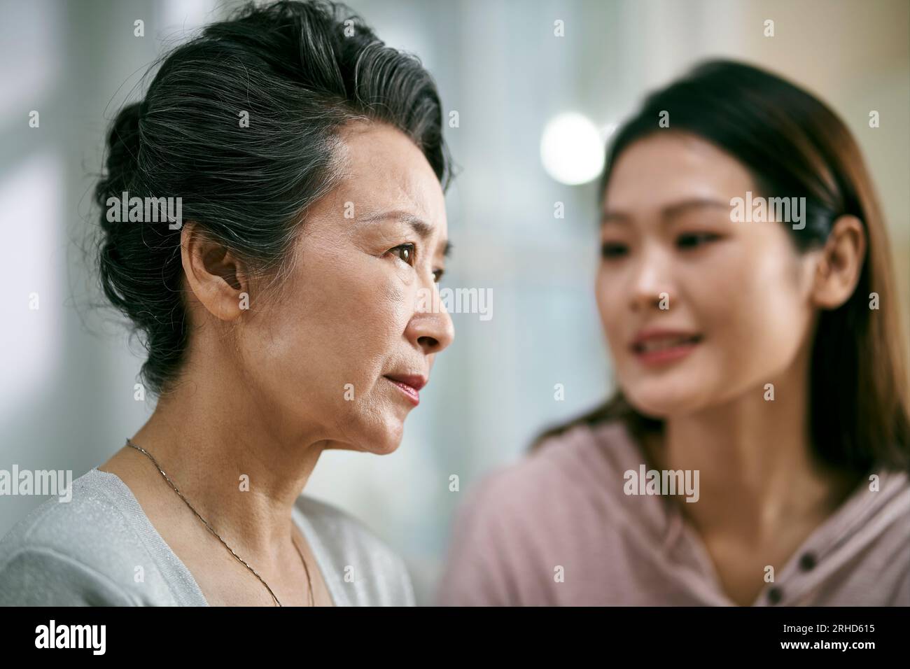Junge asiatische Erwachsenentochter tröstet Seniormutter mit psychischer Erkrankung Stockfoto