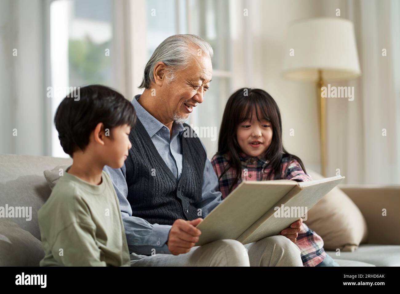 Seniorengroßvater aus Asien hat sich mit zwei Enkeln zu Hause amüsiert Stockfoto