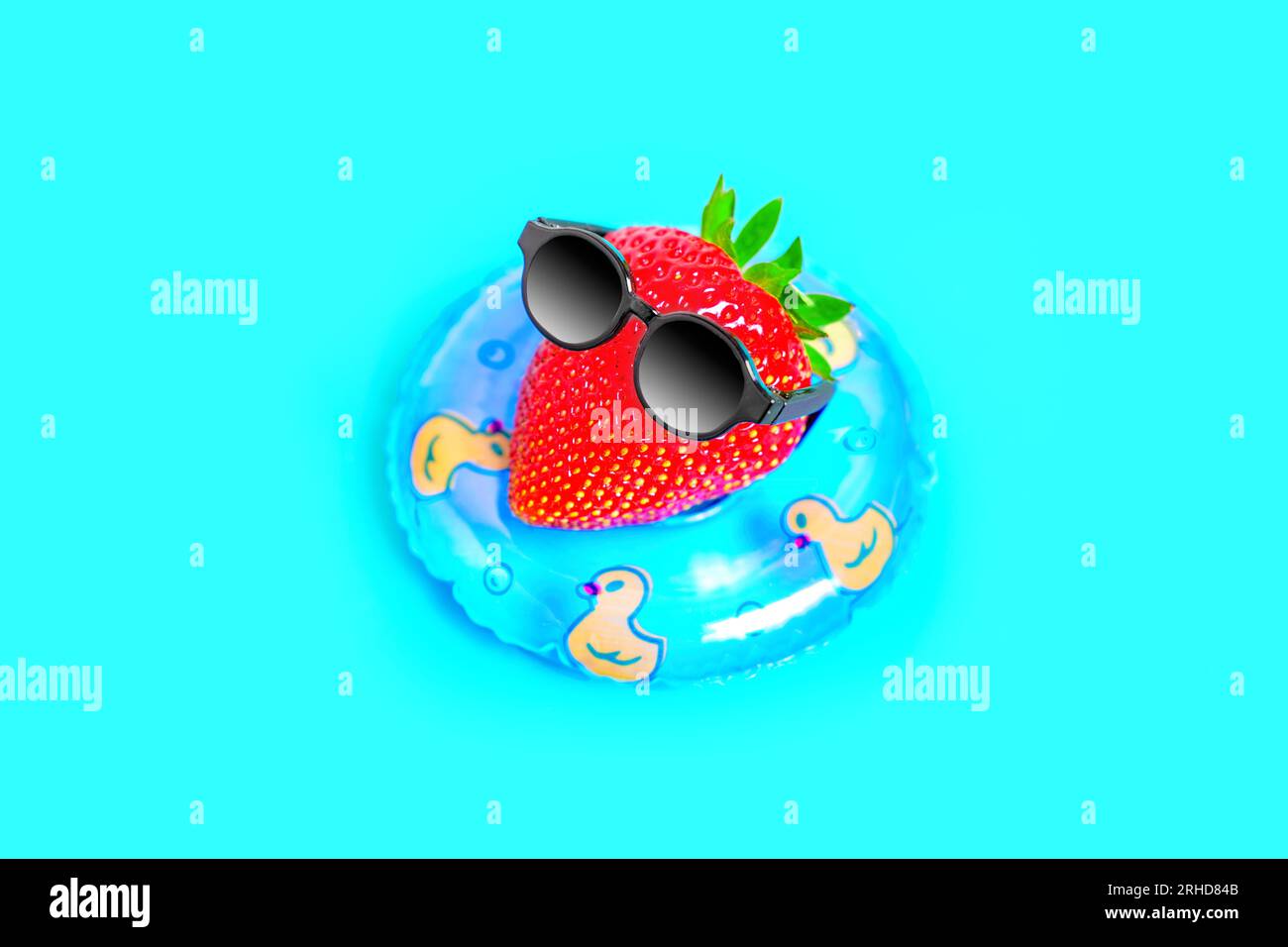 Saftige Erdbeere, verziert mit stilvoller schwarzer Sonnenbrille, schwimmt anmutig in einem Poolring. Hot Summer Escape-Konzept. Stockfoto