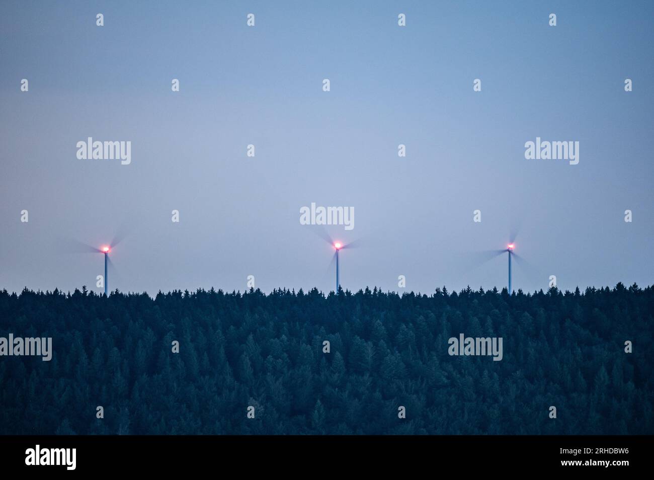 Spaichingen, Deutschland. 15. Aug. 2023. Windturbinen drehen sich im Dunkeln in einem bewaldeten Bereich. Kredit: Silas Stein/dpa/Alamy Live News Stockfoto