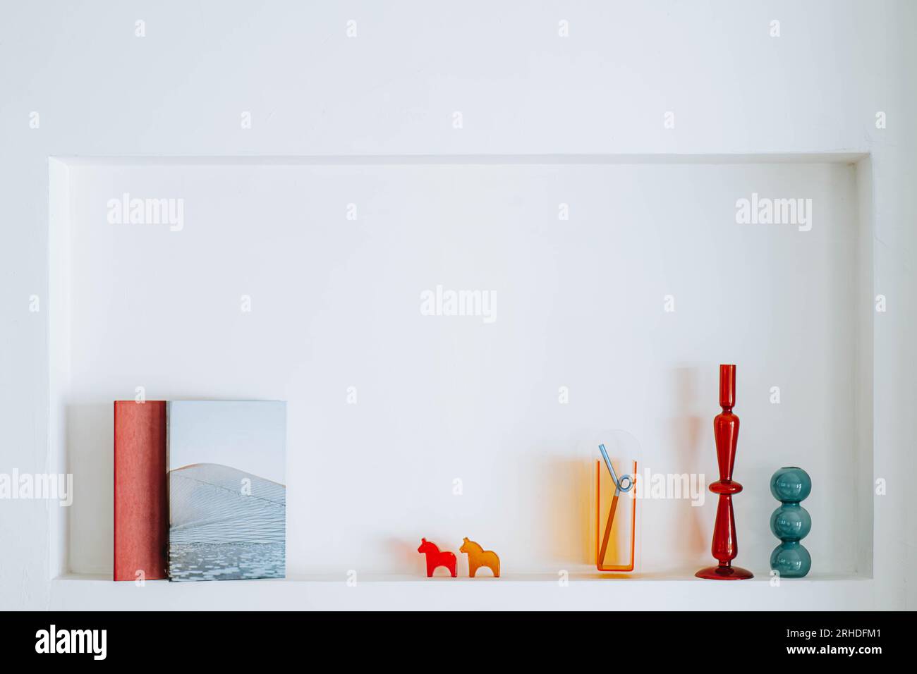 Bücher und verschiedene Dekorationen auf weißer Nook-Wand, die als Regal dient Stockfoto