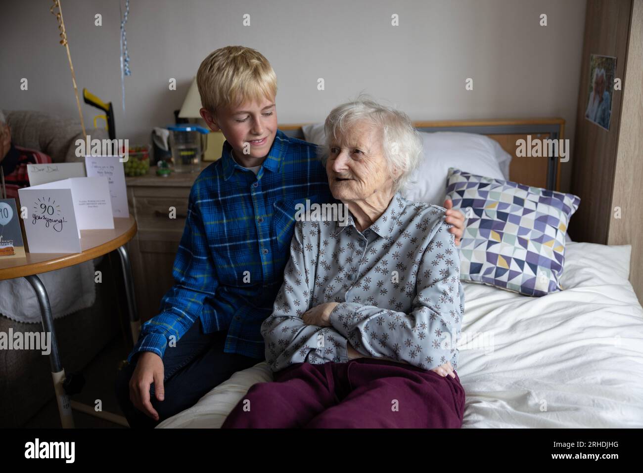 12-jähriger Junge besucht seine 85-jährige Großmutter in ihrem Pflegeheim, England, Großbritannien Stockfoto
