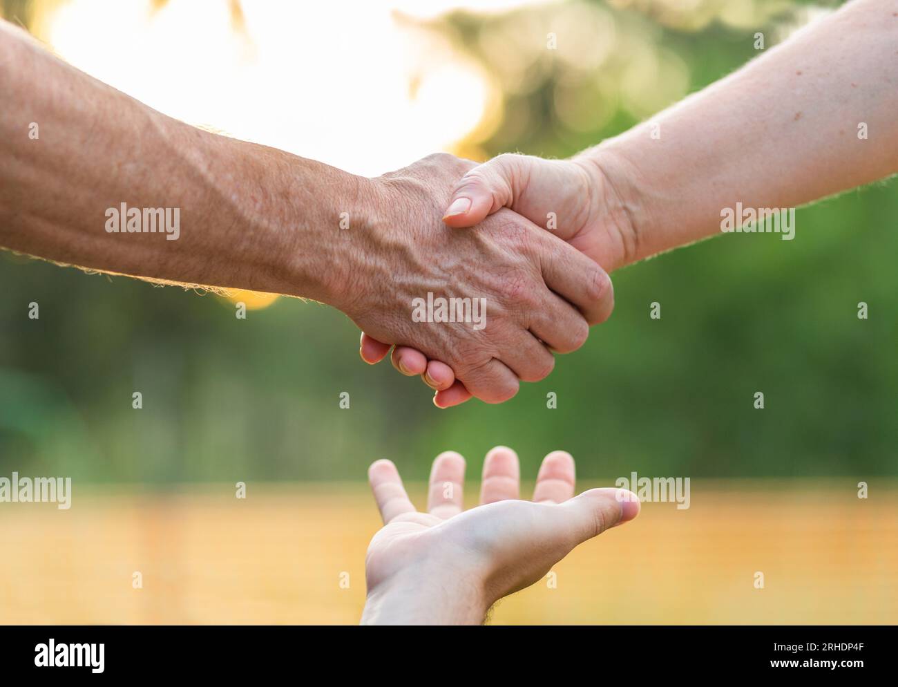 Männliche und weibliche Hände mittleren Alters schütteln sich mit der Hand des Mediators und helfen ihnen dabei, sich bei Sonnenuntergang auf das Konzept der Mediation und Beratung zu einigen Stockfoto