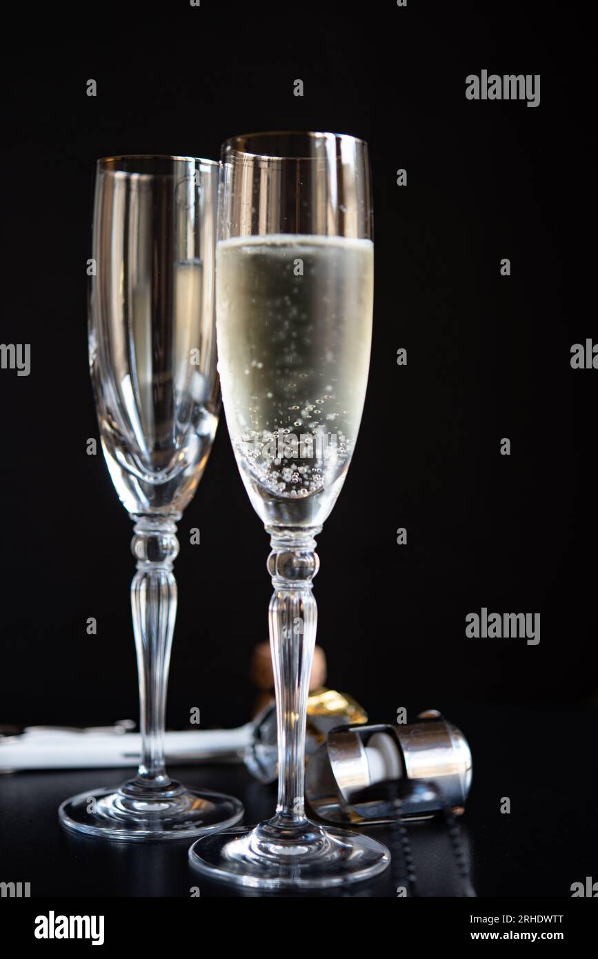 Zwei Champagnergläser auf schwarzem Hintergrund mit Öffner und Stopper Stockfoto