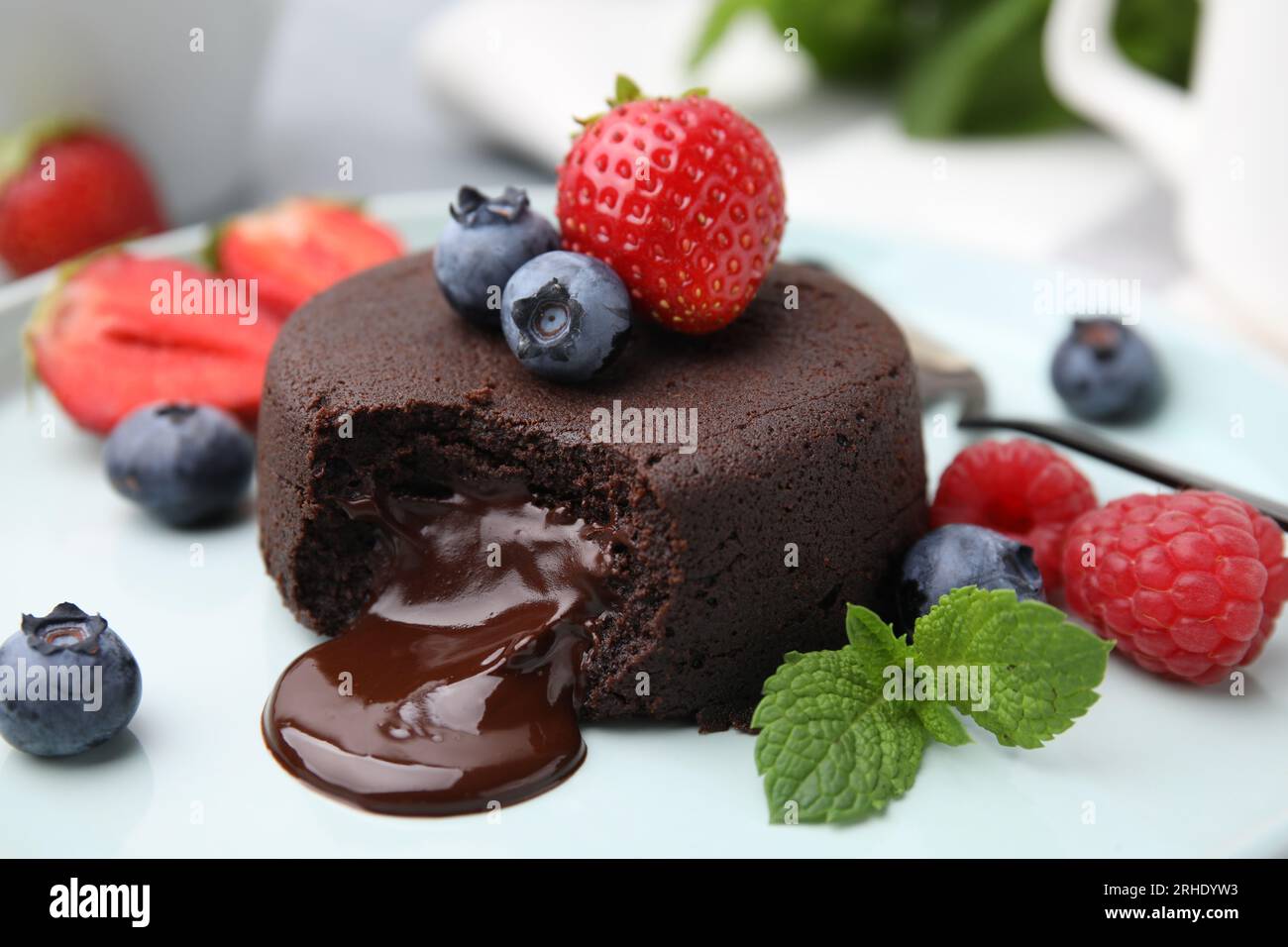 Köstliche Schokoladenfondant, Beeren und Minze auf dem Teller, Nahaufnahme Stockfoto