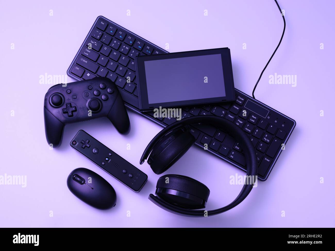 Schwarze Geräte: Gamepad, Computermaus, Tastatur, Headset und Tablet-pc. Gaming-Konzept auf violettem Hintergrund Stockfoto