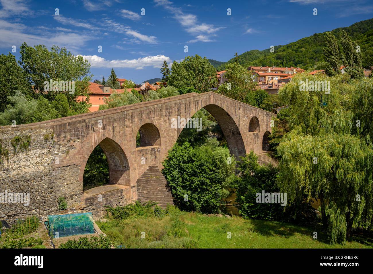 Die alte mittelalterliche Brücke, die den Fluss Ter in Sant Joan de les Abadesses überquert, mit der Stadt im Hintergrund (Ripollès, Girona, Katalonien, Spanien) Stockfoto