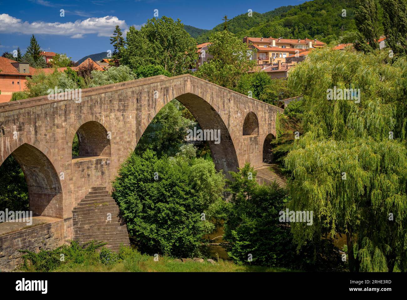 Die alte mittelalterliche Brücke, die den Fluss Ter in Sant Joan de les Abadesses überquert, mit der Stadt im Hintergrund (Ripollès, Girona, Katalonien, Spanien) Stockfoto