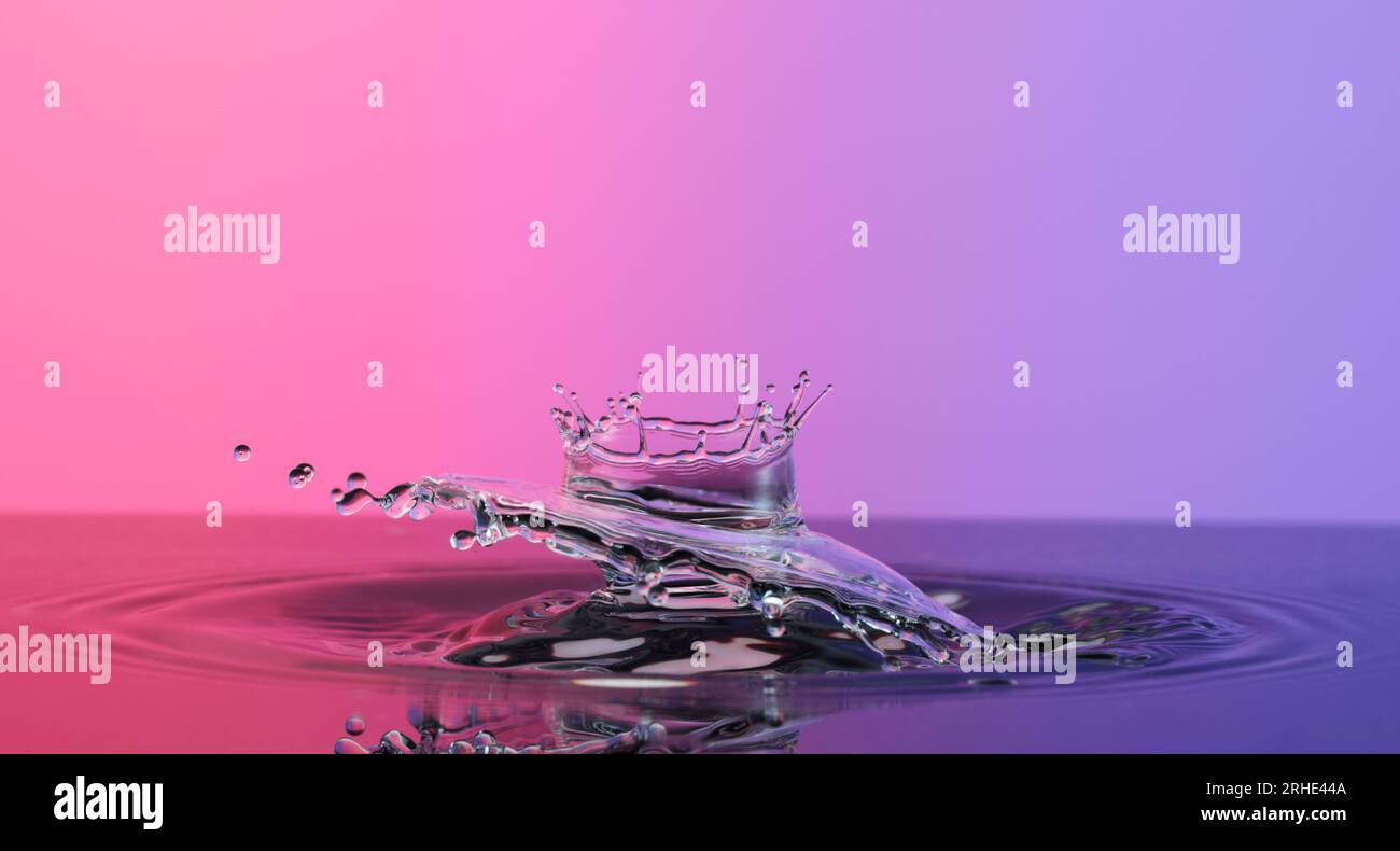 Wasserspritzer wie eine Krone auf einer Nahaufnahme mit farbigem Hintergrund Stockfoto