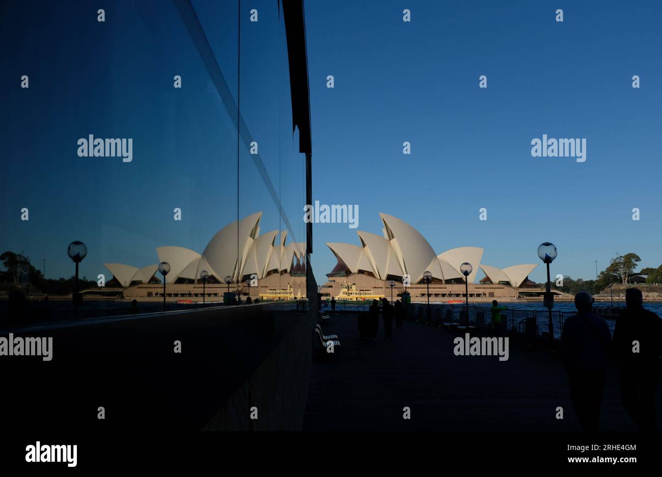 Sydney Opera House und eine Spiegelbilderspiegelung des Opernhauses segeln mit einer weiten Weite klaren blauen australischen Himmels und Menschen in Silhouette Stockfoto