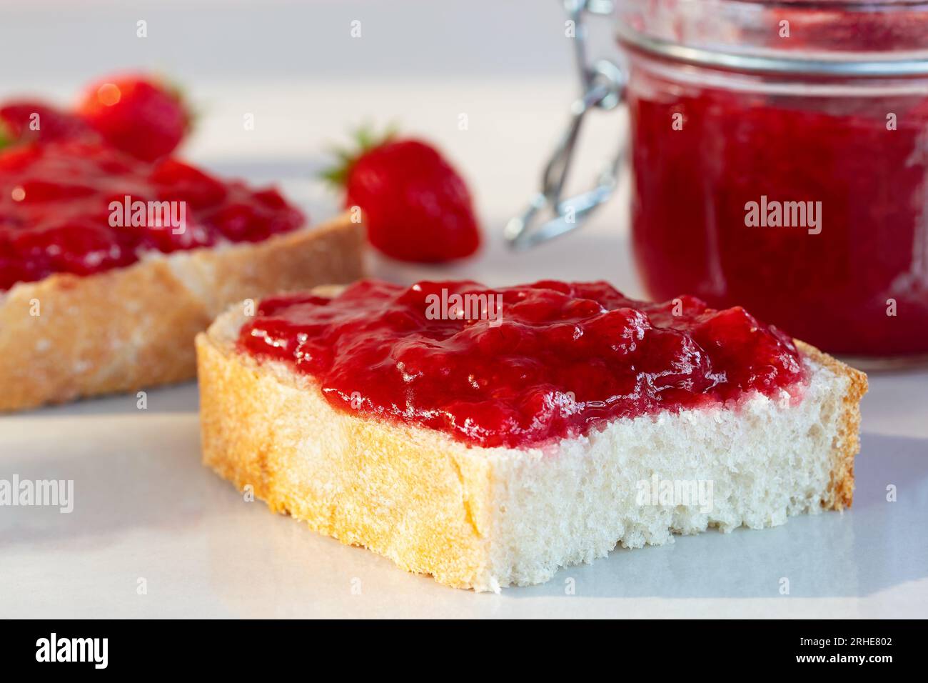 Weizenbrot mit aufgestrichener Erdbeermarmelade auf dem Tisch. Stockfoto
