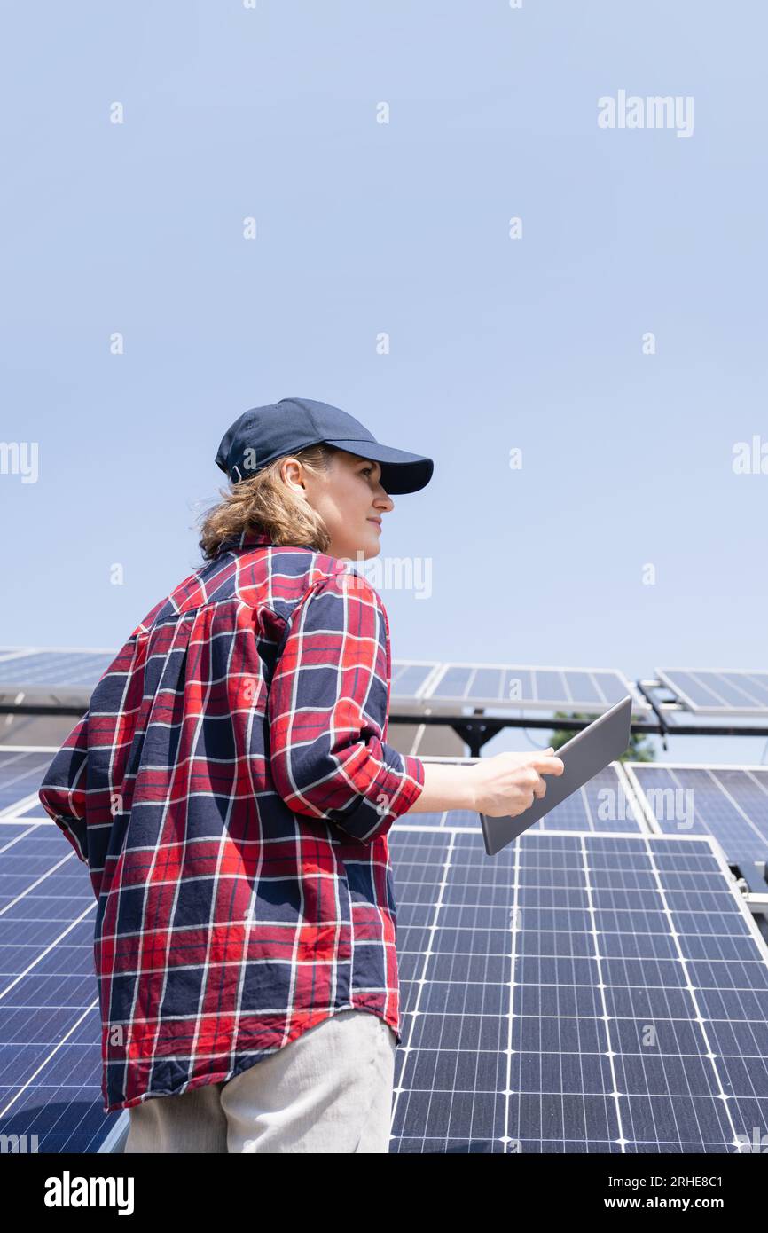 Frau mit digitalem Tablet vor dem Hintergrund eines mobilen Solarkraftwerks. Stockfoto