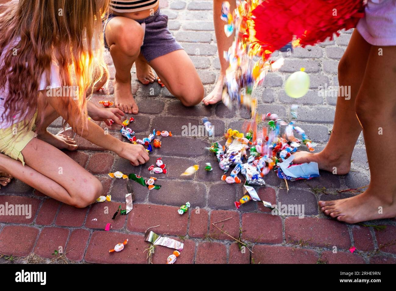Kinder sammeln Süßigkeiten und Überraschungen, die aus einem piñata bei einer Kinderparty fielen Stockfoto