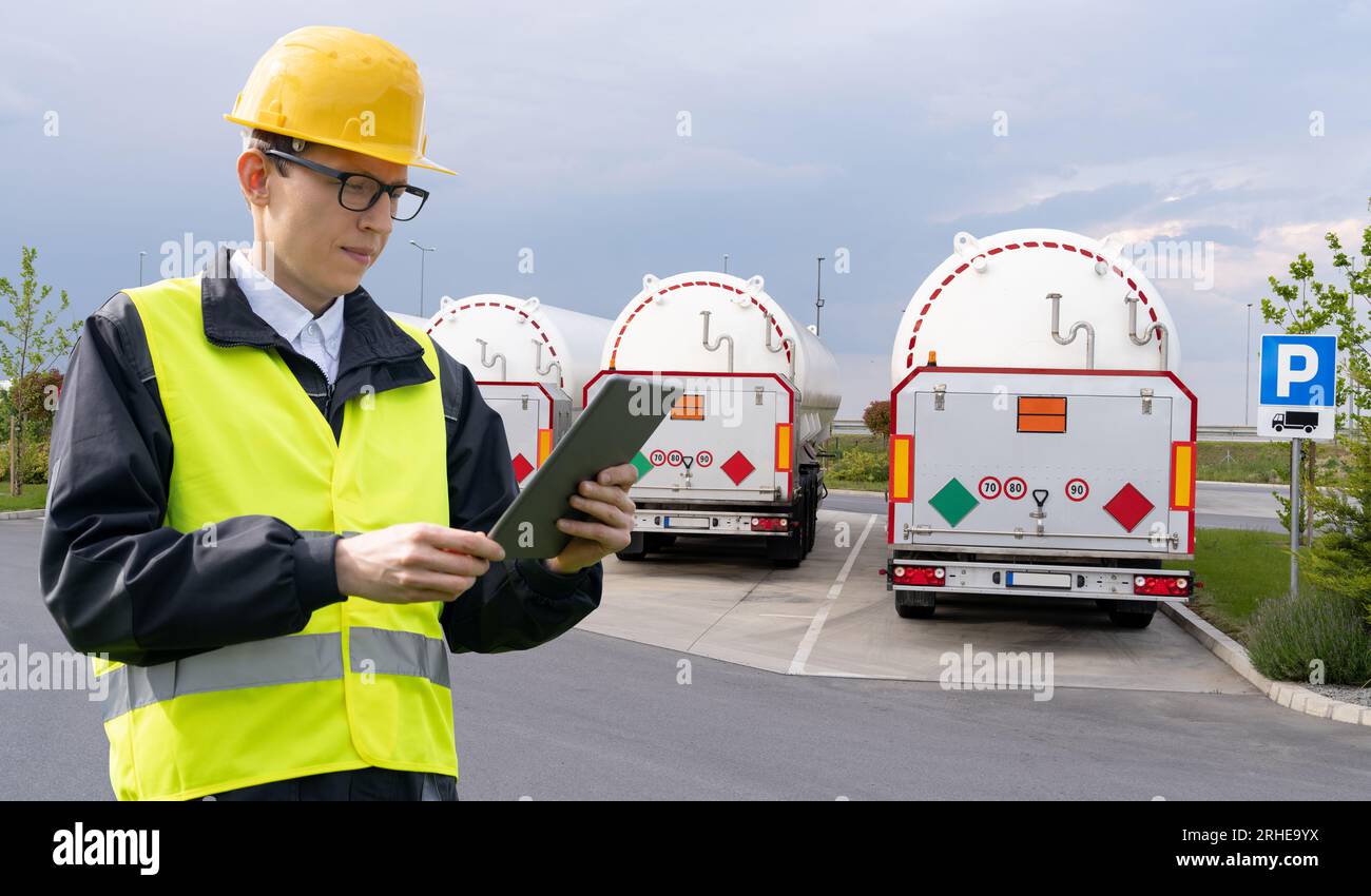 Mann mit digitalem Tablet auf einem Hintergrund von Tankaufliegern. Flüssiggastransport. Stockfoto