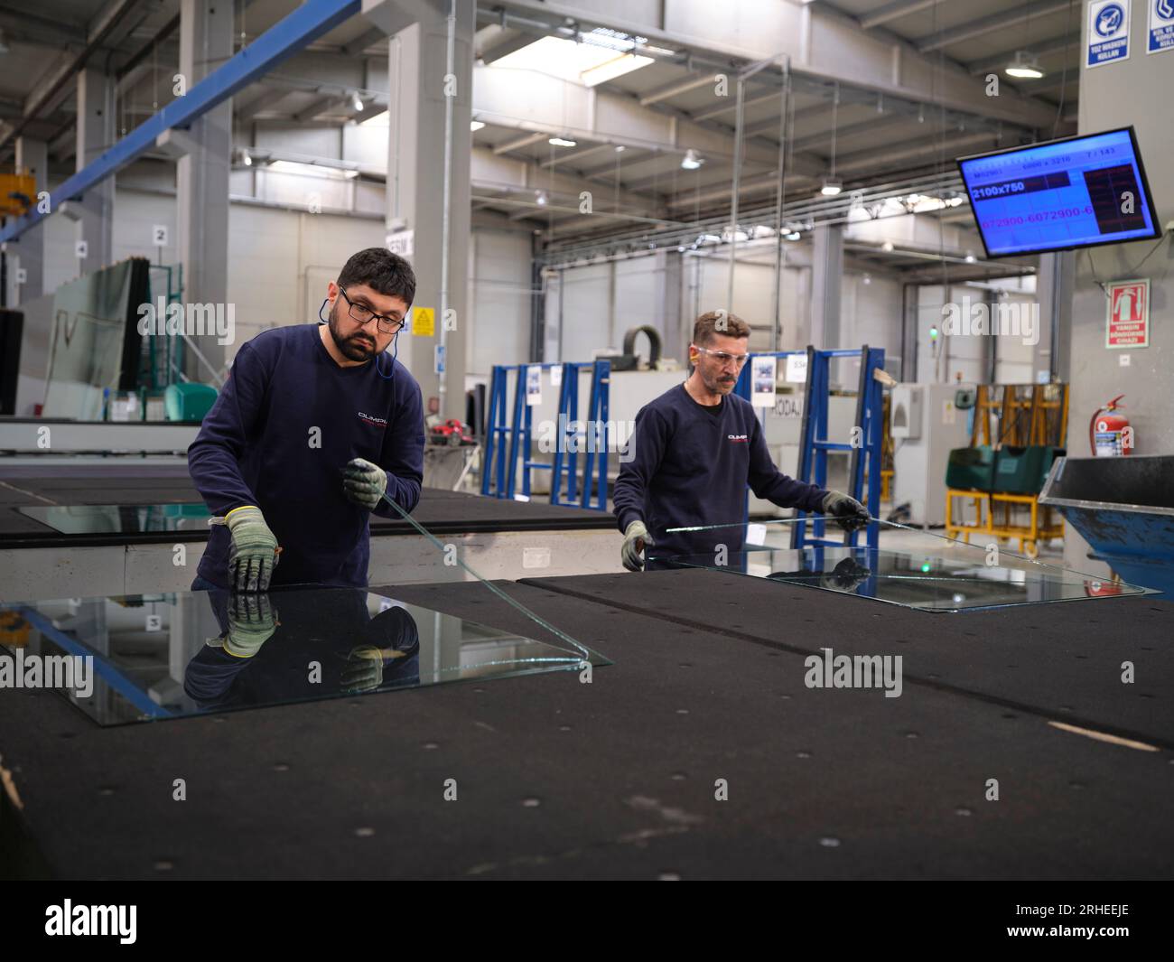 Werk für die Herstellung von Fenstern und Windschutzscheiben. Manueller Arbeiter, der PVC-Fenster und Fahrzeugfenster zusammenbaut. Arbeiter, die Glasplatten im Lager verpacken Stockfoto