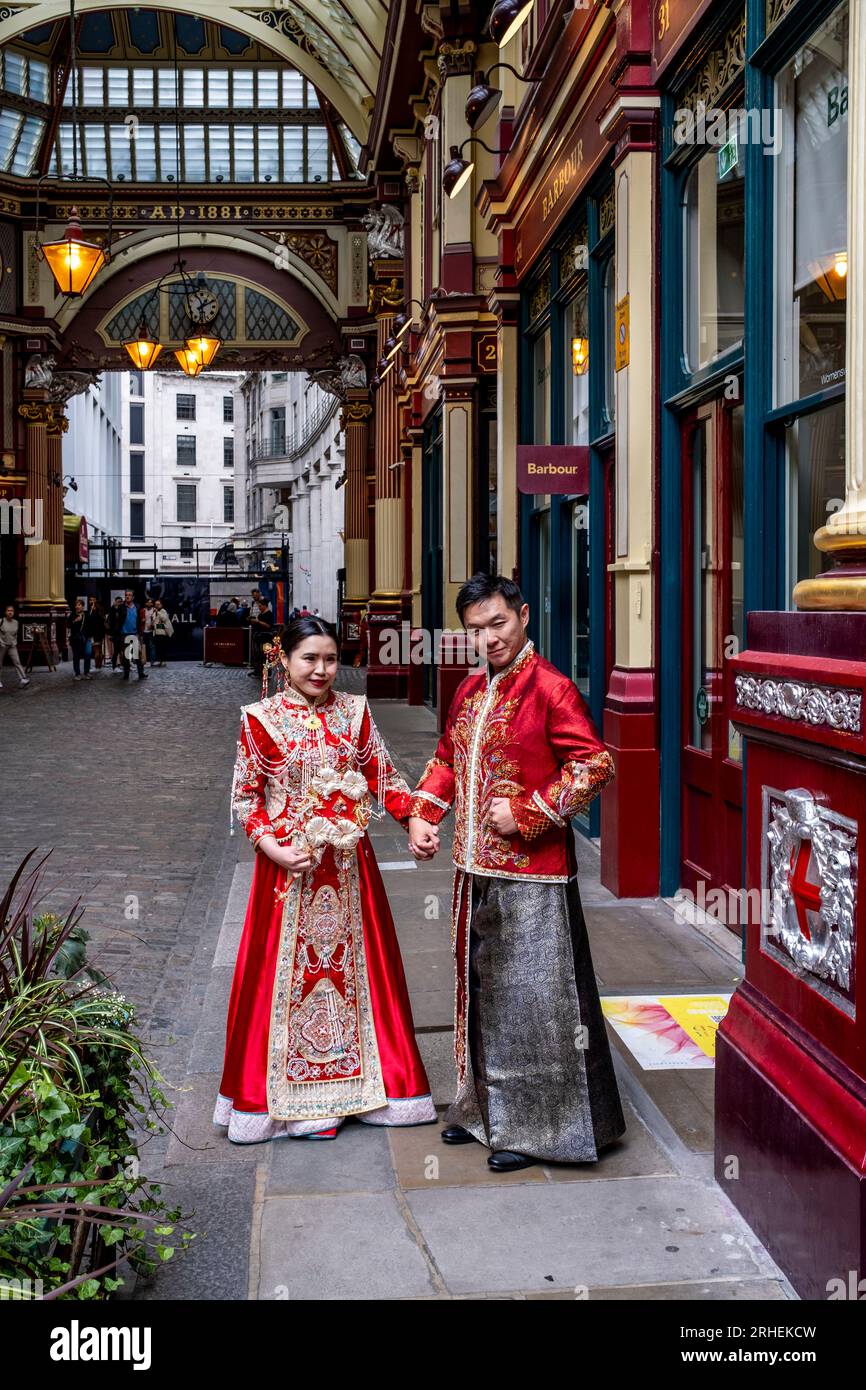 Ein chinesisches Paar posiert vor dem Barbour Luxury Clothes Shop in Leadenhall Market, London, Großbritannien, für Hochzeitsfotos in traditionellem Kostüm. Stockfoto