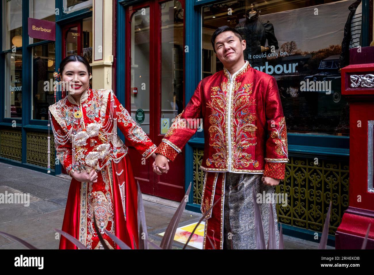 Ein chinesisches Paar posiert vor dem Barbour Luxury Clothes Shop in Leadenhall Market, London, Großbritannien, für Hochzeitsfotos in traditionellem Kostüm. Stockfoto