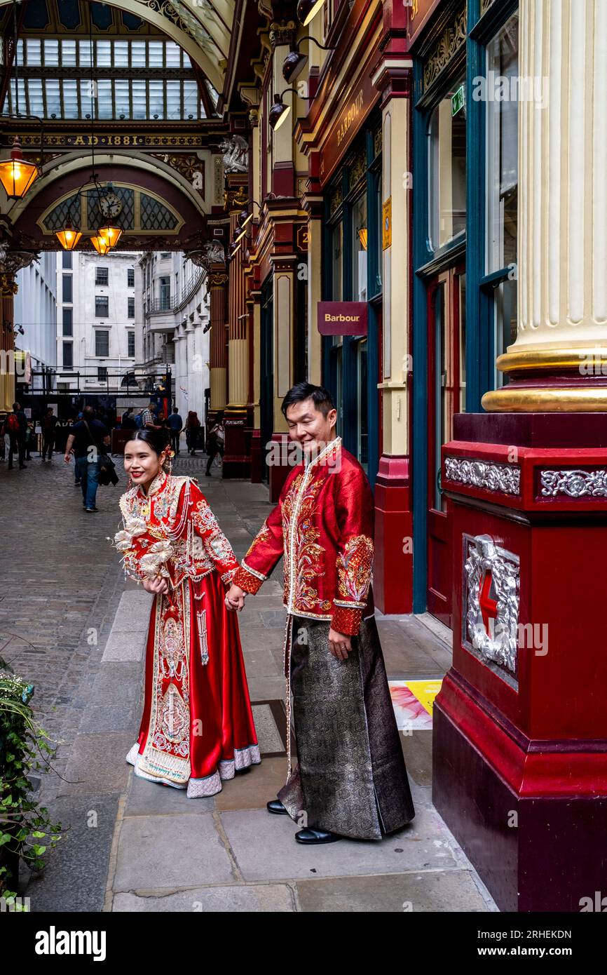 Ein chinesisches Paar posiert vor dem Barbour Luxury Clothes Shop in Leadenhall Market, London, Großbritannien, für Hochzeitsfotos in traditionellem Kostüm. Stockfoto