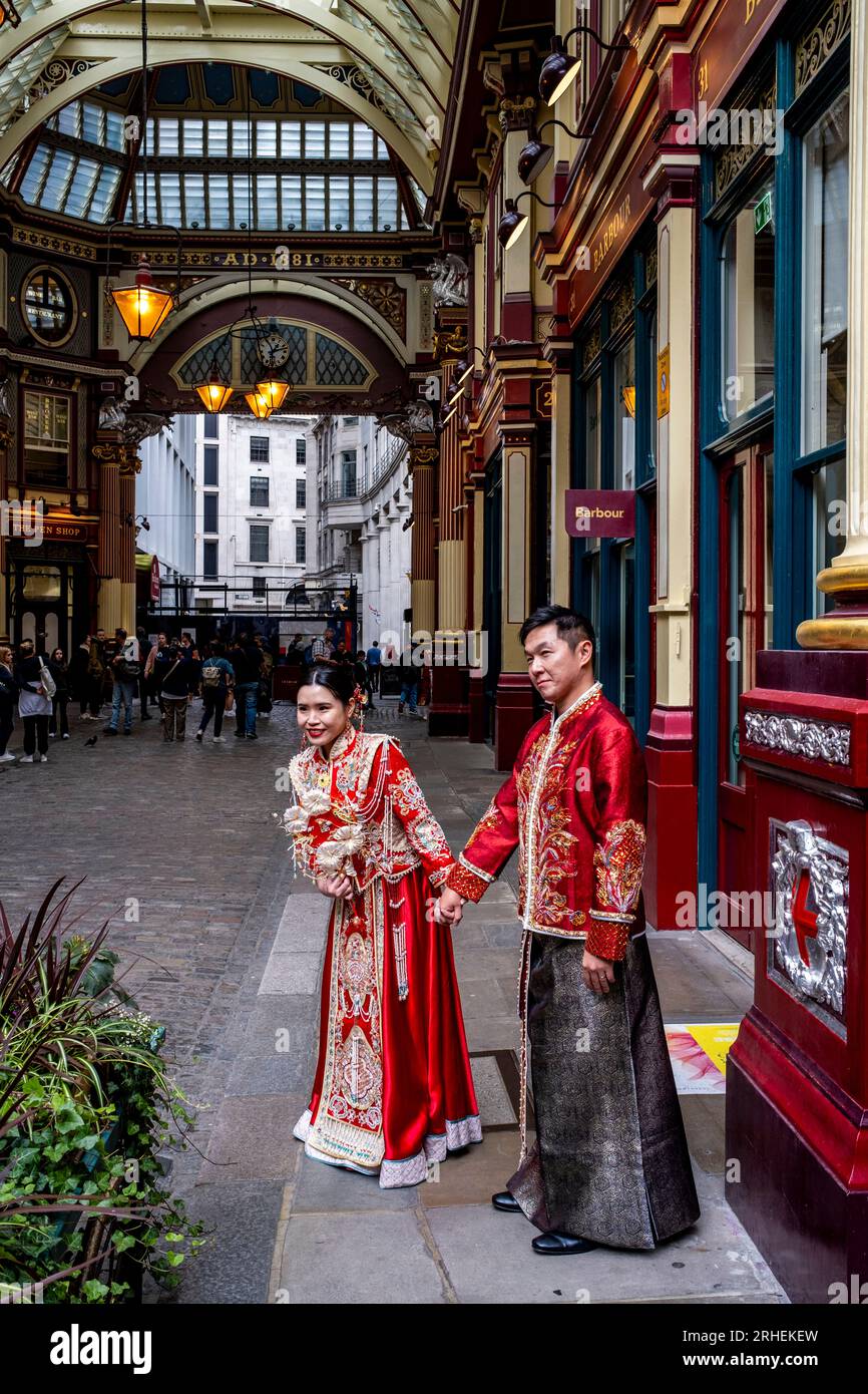 Ein chinesisches Paar posiert vor dem Barbour Luxury Clothes Shop in Leadenhall Market, London, Großbritannien, für Hochzeitsfotos in traditionellem Kostüm. Stockfoto