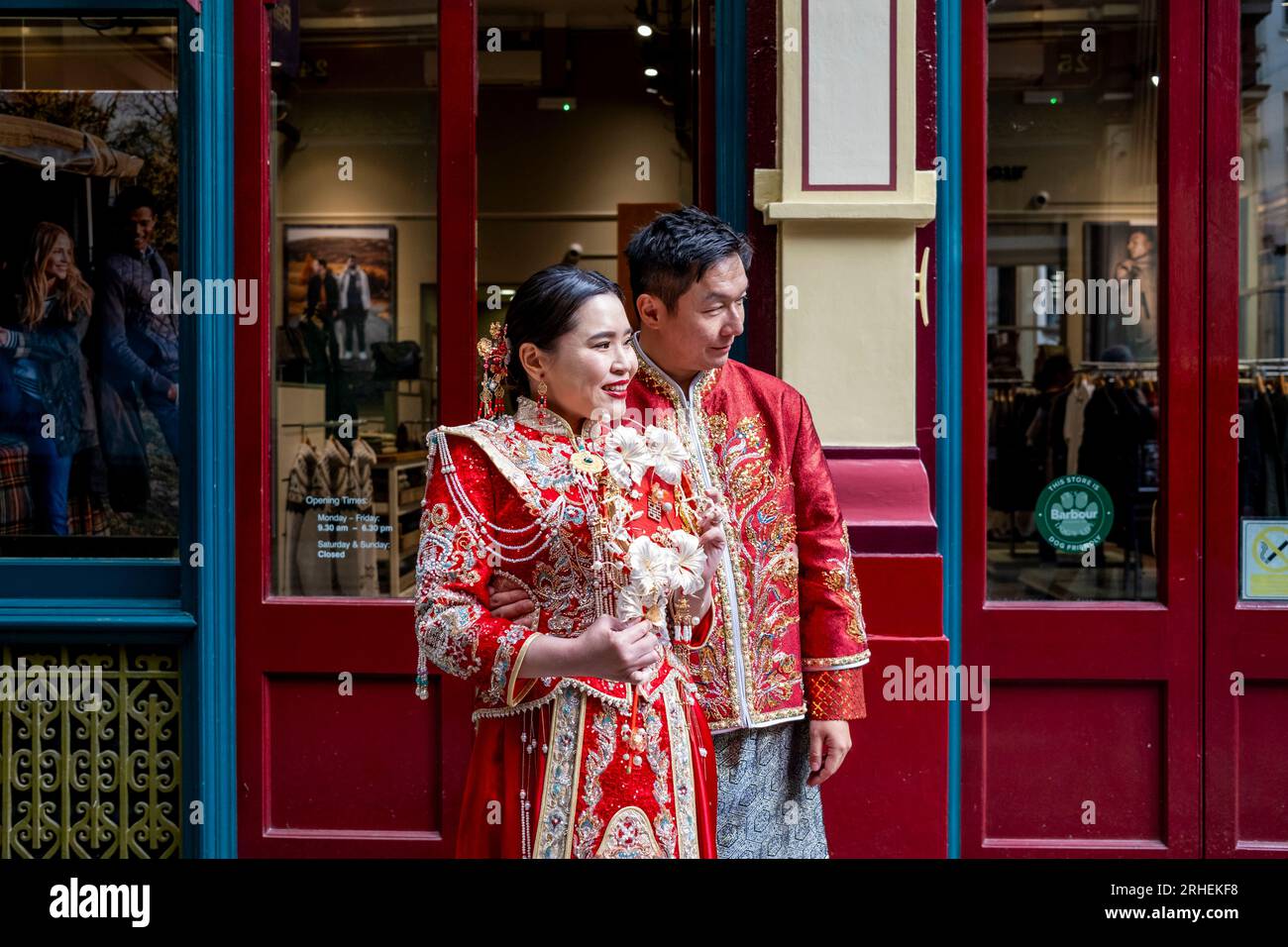 Ein chinesisches Paar posiert vor dem Barbour Luxury Clothes Shop in Leadenhall Market, London, Großbritannien, für Hochzeitsfotos in traditionellem Kostüm. Stockfoto