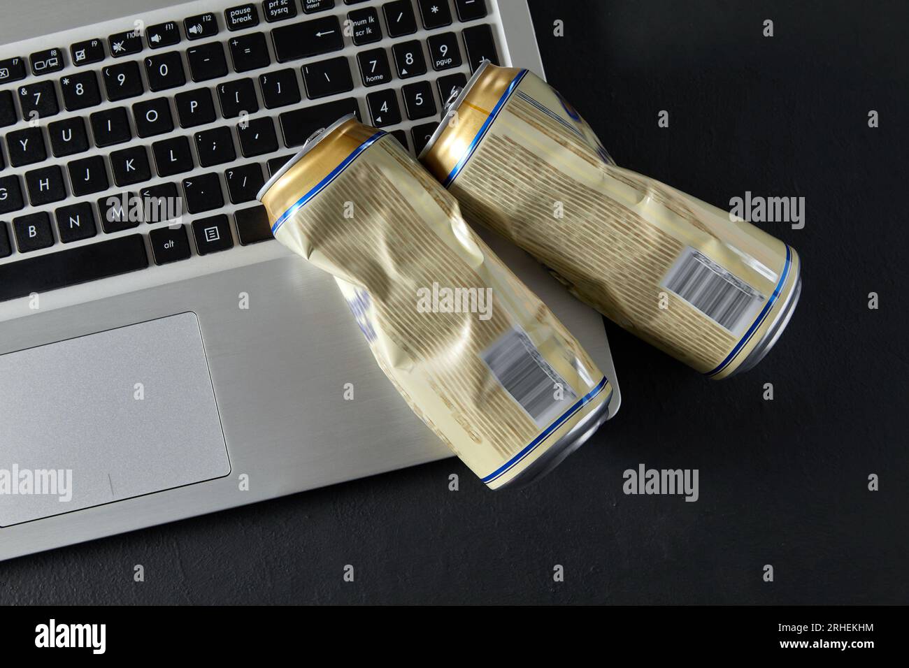 Leere zerknitterte Bierdosen auf Laptop-Tastatur auf schwarzem Hintergrund. Trunkenheit kämpft in sozialen Medien. Scheidungsursache in der Familie Stockfoto