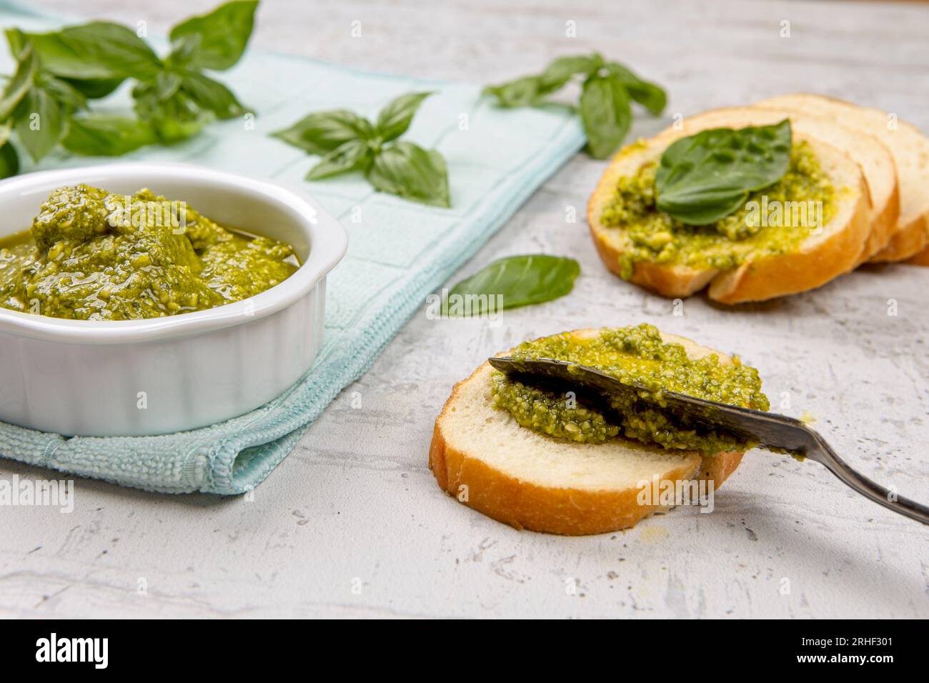 Ein Foto, wie frisches Pesto auf kleine Brotscheiben im Studio verteilt wird. Stockfoto