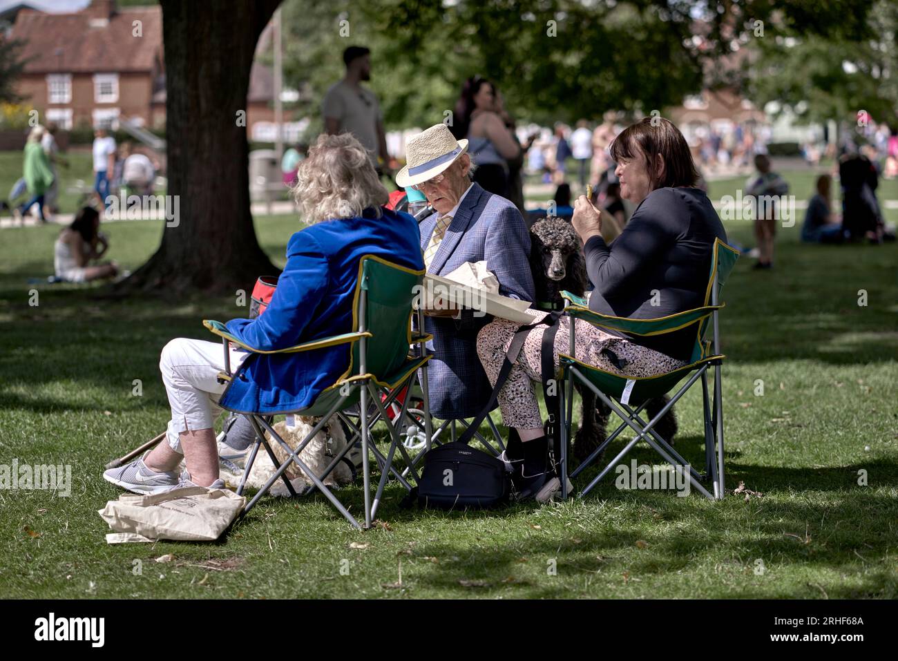 Die Leute sitzen draußen auf Klappstühlen und genießen das englische Sommerwetter. England Großbritannien Stockfoto