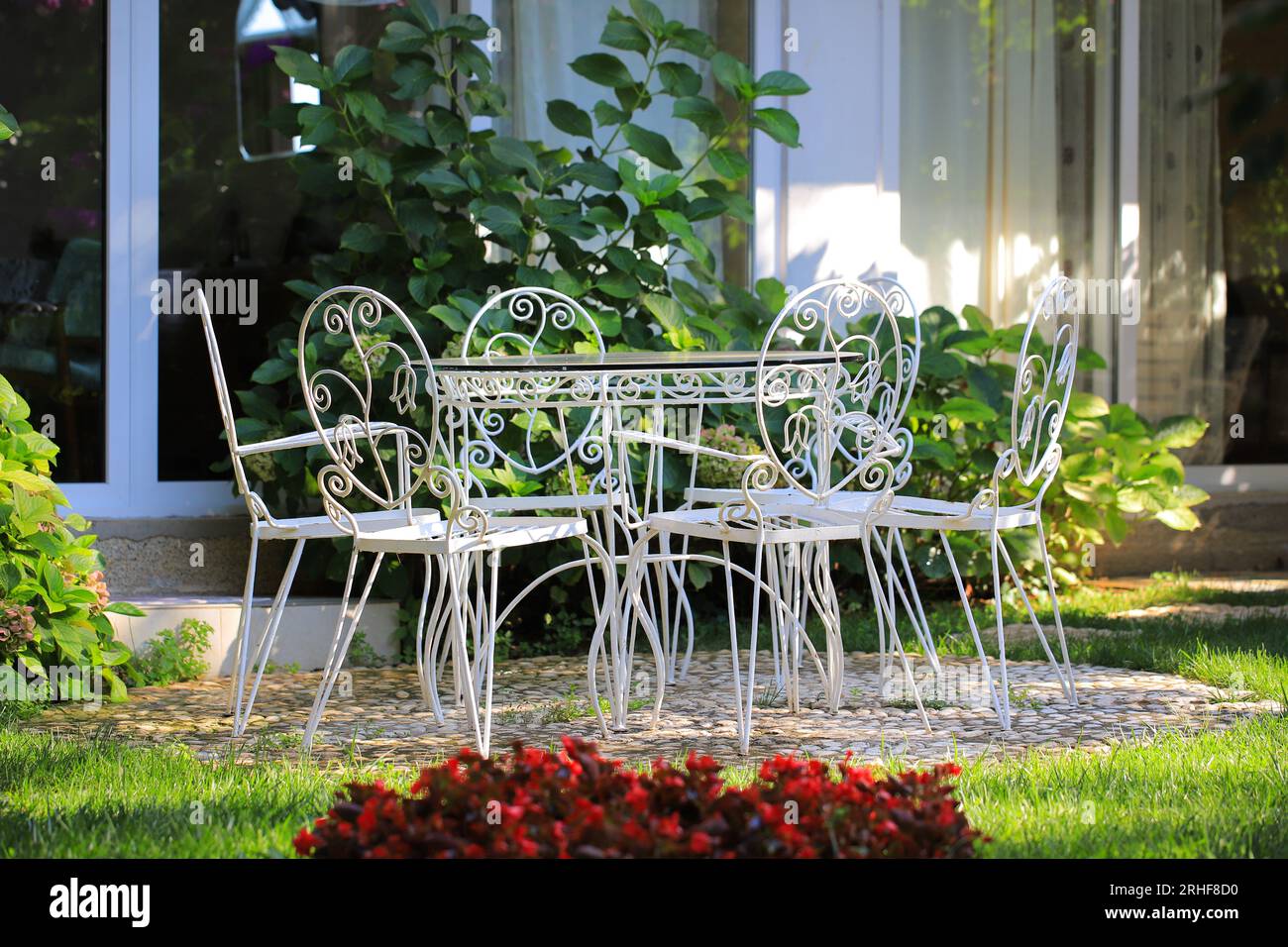Vintage-Tisch aus weißem Schmiedeeisen mit Stühlen im Freien Stockfoto
